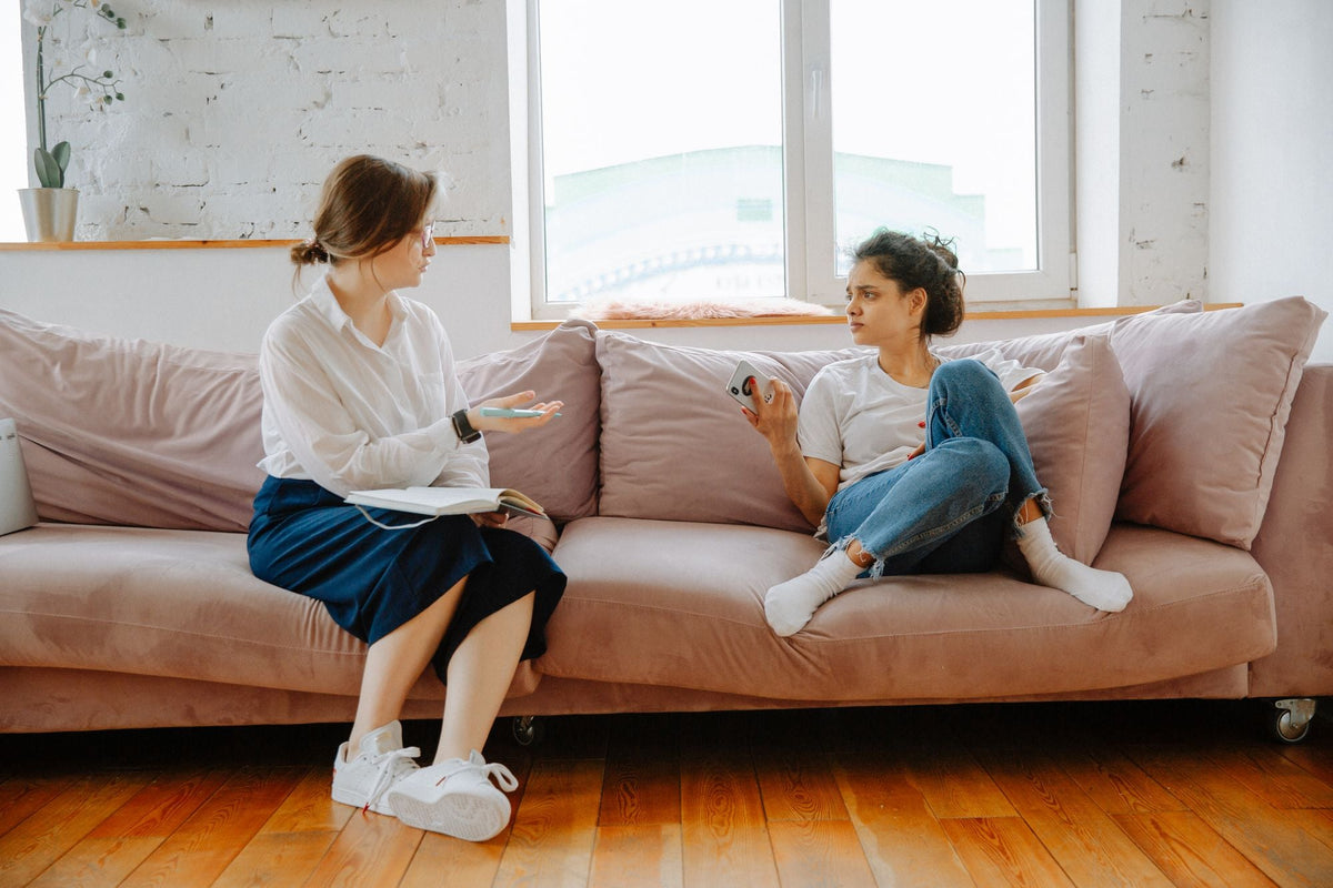 Zwei Frauen im Gespräch auf einem Sofa in einer Beratung