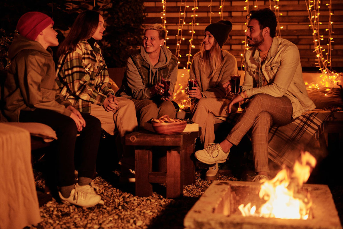 Freunde sitzen abends am Feuer und führen Deep Talk Gespräche