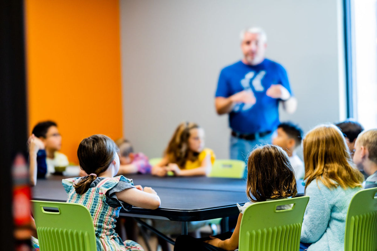Kinder hören im bunten Klassenzimmer einer Lehrerin zu