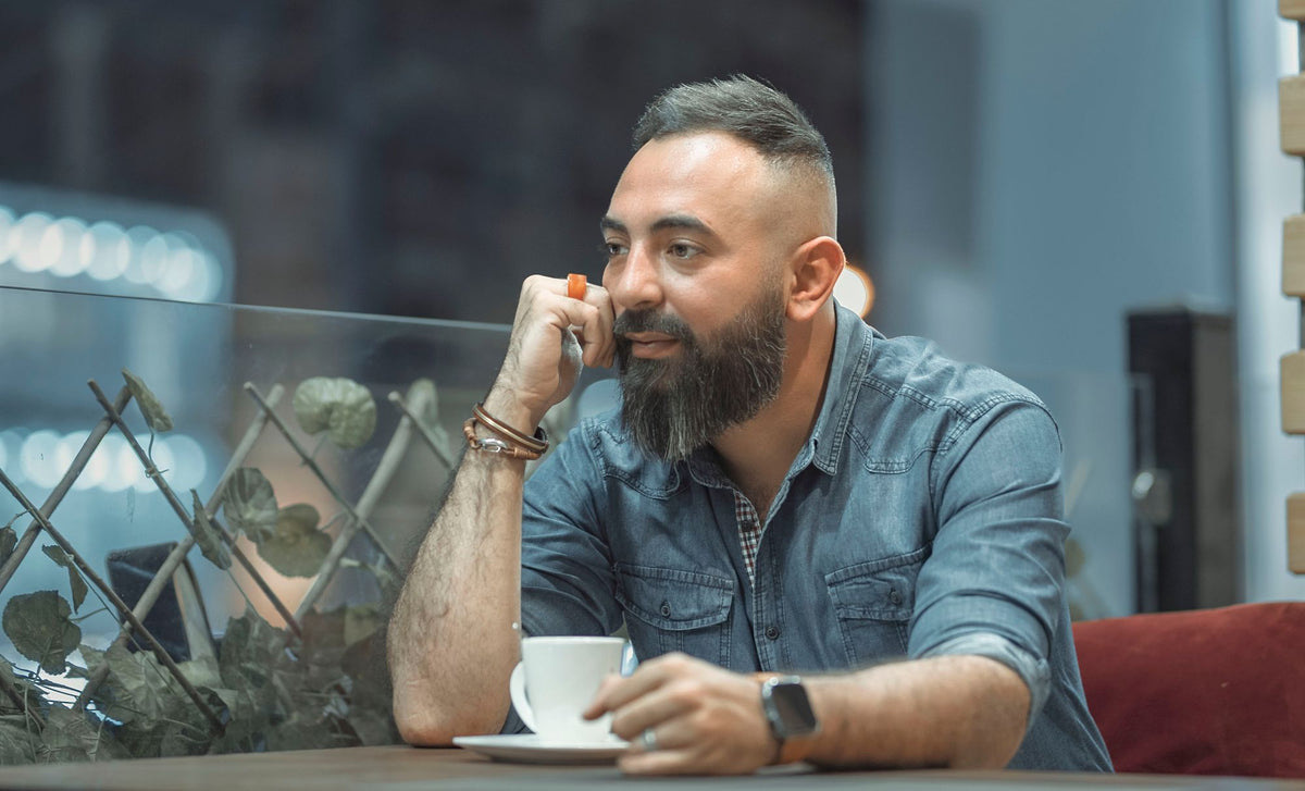 Mann sitzt mit Kaffee im Café und denkt nach
