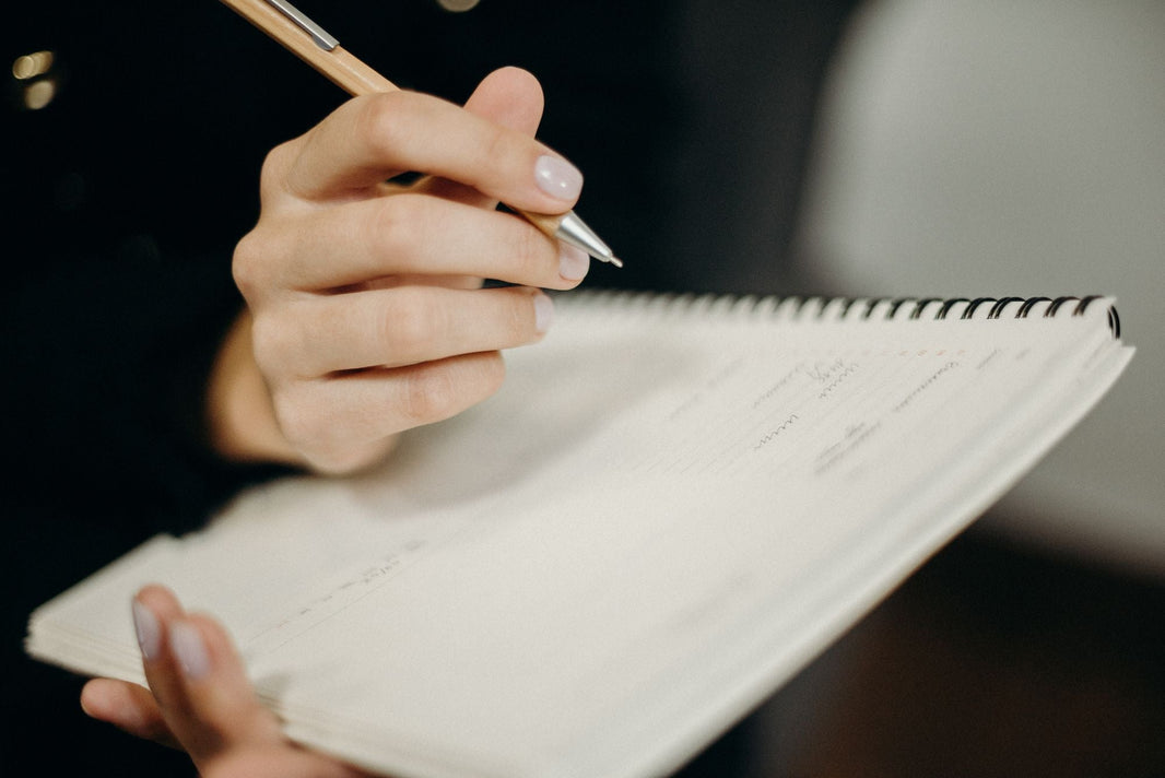Hand schreibt mit einem Stift in ein Notizbuch