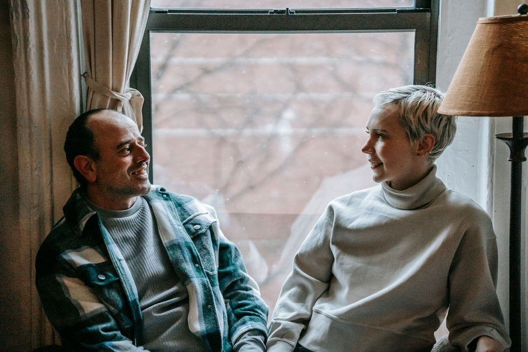 Zwei Menschen sitzen am Fenster und lachen zusammen