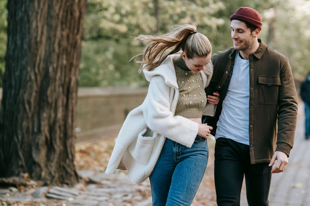 Junges Paar geht im Herbst Arm in Arm durch den Park