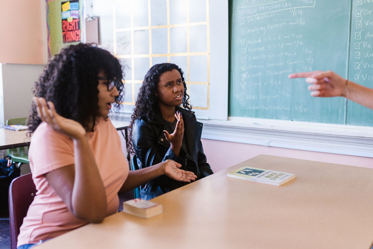 Schülerinnen diskutieren mit ihrem Lehrer im Klassenzimmer