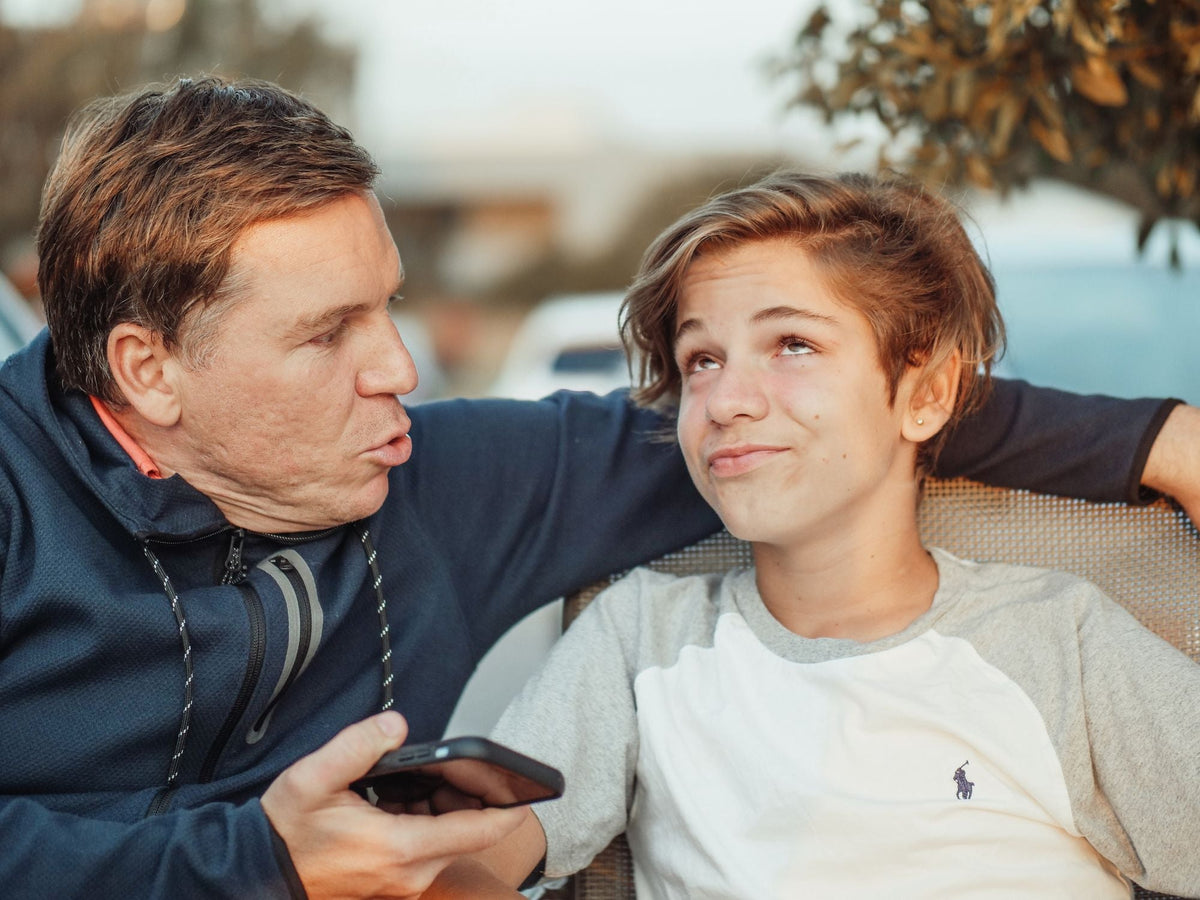 Vater und Sohn unterhalten sich lachend auf dem Sofa