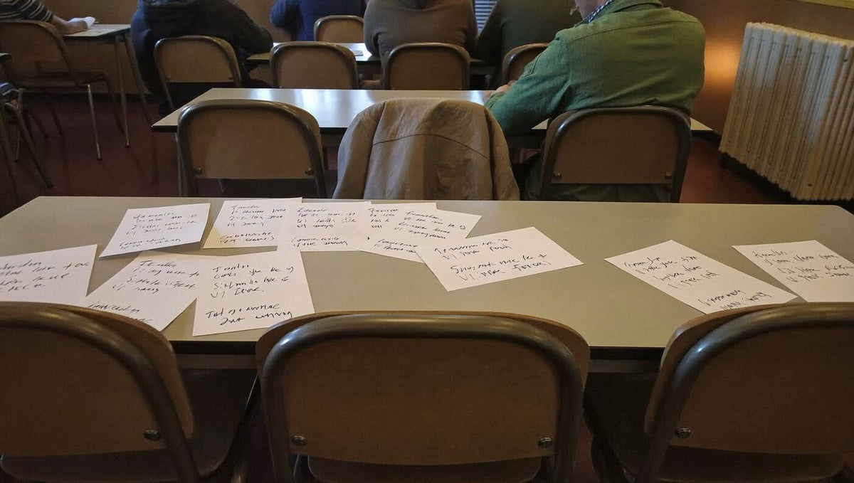 Elternabend zum Thema Kindern Werte vermitteln: Tische mit handgeschriebenen Wertesätzen, Eltern im Hintergrund